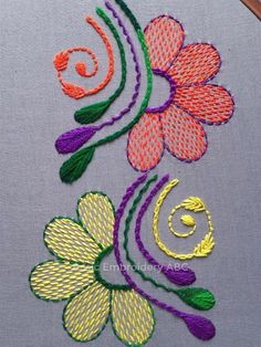 the embroidery design is done with different colors and shapes, including two flowers on each side