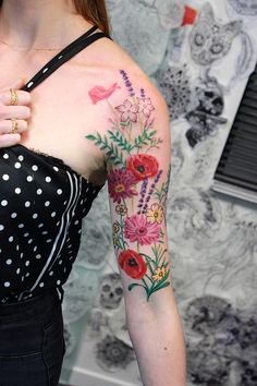 a woman wearing a black and white polka dot top with flowers on her arm,