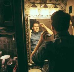 a man sitting in front of a mirror brushing his hair