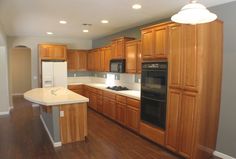 an empty kitchen with wooden cabinets and white counter tops, along with hard wood flooring