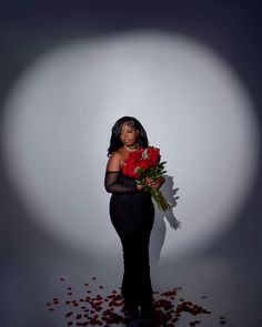 a woman standing in front of a white background holding roses