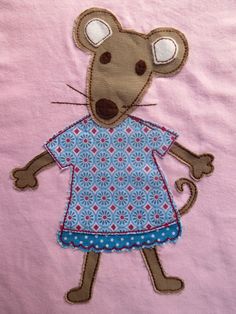 a small embroidered mouse in a blue dress on a pink shirt with red and white dots