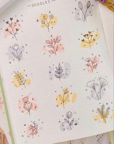 an open notebook with doodles on it and flowers in the pages next to it