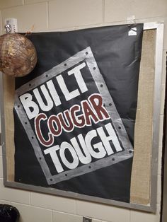 a bulletin board with the words built cough tough and a ball hanging from it's side