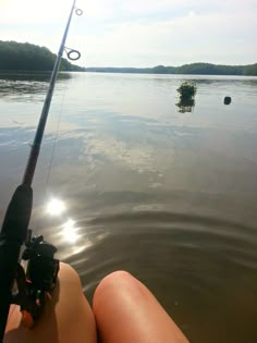 a person is fishing in the water with their feet propped up on the boat's front end