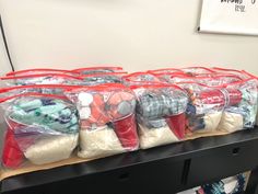 several bags filled with various items sitting on top of a wooden table in front of a white wall