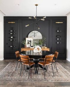 a dining room with black walls and wooden chairs