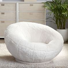 a white bean bag chair sitting on top of a carpeted floor next to a potted plant