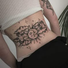 a woman's stomach with the sun and clouds tattoo on her belly, while she is wearing black pants