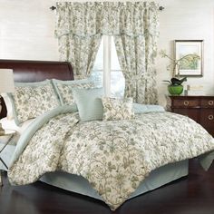 a bedroom with a bed, dresser and window covered in floral comforter set on top of a hard wood floor