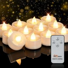 many lit candles with remote controls on a black surface