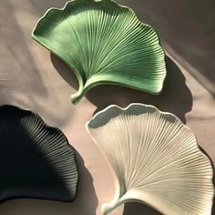 three large leaf shaped dishes sitting on top of a bed