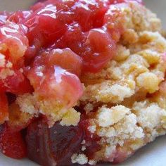 a close up of a piece of food on a plate with crumbs and jelly