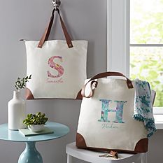 two personalized tote bags hanging on the wall next to a table with flowers