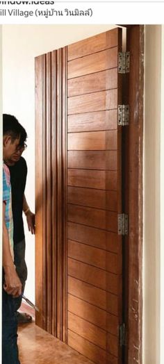 two men are standing in front of a wooden door and one is using a nailing machine