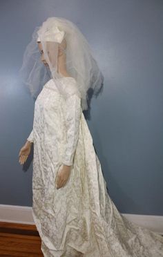 a mannequin wearing a white wedding dress and veil in front of a blue wall