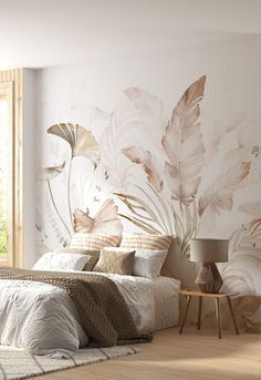 a bedroom with a bed, nightstand and wall mural in the background that has leaves on it