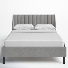 an upholstered bed with white sheets and pillows