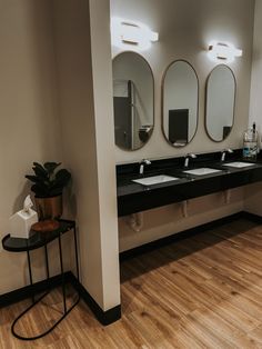 a bathroom with three sinks and mirrors on the wall