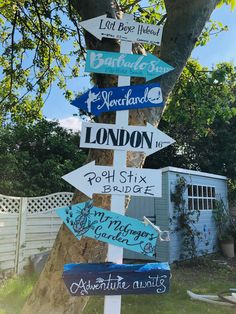 a wooden sign post with many different signs on it's side in front of a tree