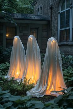 three lighted ghost statues in front of a house