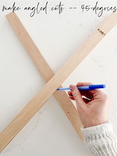 a person holding a pencil in their left hand and making an x shape with wood