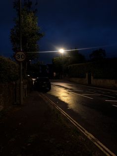 a car is parked on the side of the road at night with its lights on