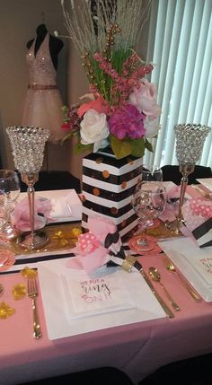 the table is set with pink and white flowers, gold place settings, and napkins