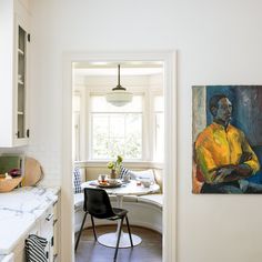 a kitchen with a painting on the wall next to a dining room table and chairs