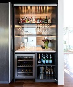 If you plan on adding in many new appliances or lighting when renovating, it may mean your home needs to be rewired. Cool bar set up with drinks fridge, wine fridge, pocket door, mirrored splashback, marble benchtop, charcoal veneer shelving, backlights Home Bar Kitchen, Home Kitchen Bar, Home Cocktail Bar