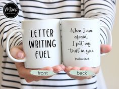 two coffee mugs with writing on them in front of a woman's striped shirt