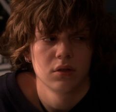 a close up of a person wearing a black shirt and hair in the background is a wall