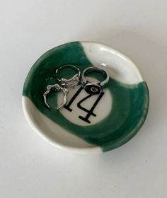 a small green and white bowl with a pair of scissors in the shape of a horse