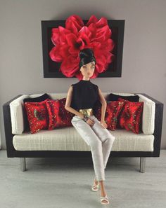 a woman sitting on top of a white couch next to a red and black flower