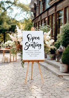 an open seating sign sitting on top of a wooden easel in front of a building