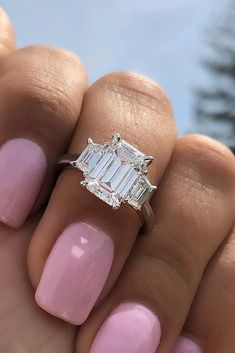 a woman's hand holding a pink manicure with a diamond ring on it