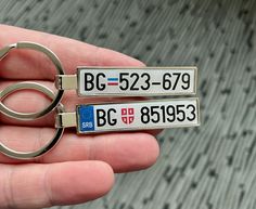 someone is holding two different key chains in their hand, one with the letter bg 533 - 699