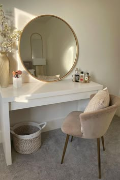 a white desk with a mirror and chair in front of it, next to a flower vase