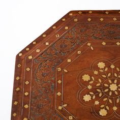 an intricately designed wooden table with gold accents on the top and bottom edge, against a white sky background