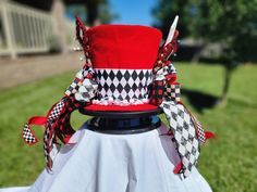 a red and black top hat sitting on top of a white cloth covered table in the grass