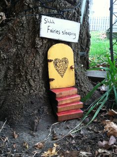 a yellow door with a heart on it is next to a tree and has a sign that says shh fawnes sleeping