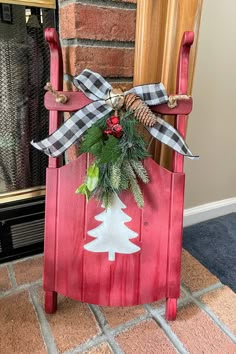 a red rocking chair with a christmas tree decoration on the back and plaid ribbon tied around it