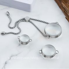 three silver teapots on a white marble counter top with a box in the background