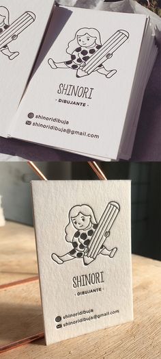 two business cards sitting on top of a wooden table next to an envelope with a cartoon character