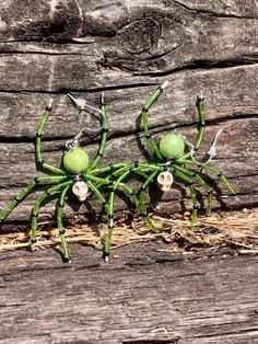 two green spider figurines sitting on top of a wooden floor next to each other