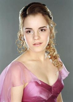 a woman in a pink dress posing for a photo with her hair pulled up into a pony tail