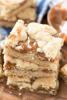 several pieces of cake sitting on top of a wooden cutting board with caramel sauce in the background