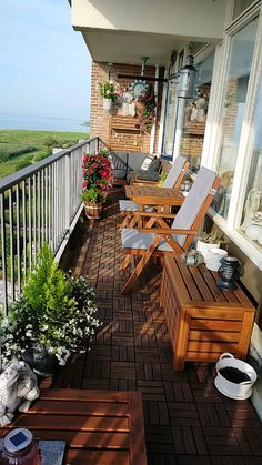 a wooden deck with chairs and potted plants on the top floor next to an open door