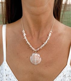 a woman wearing a necklace with shells on it