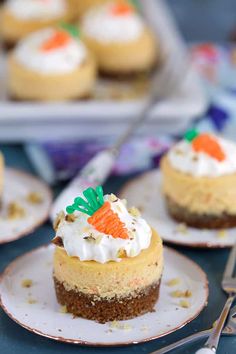 small carrot cupcakes with whipped cream and sprinkles on plates next to silverware